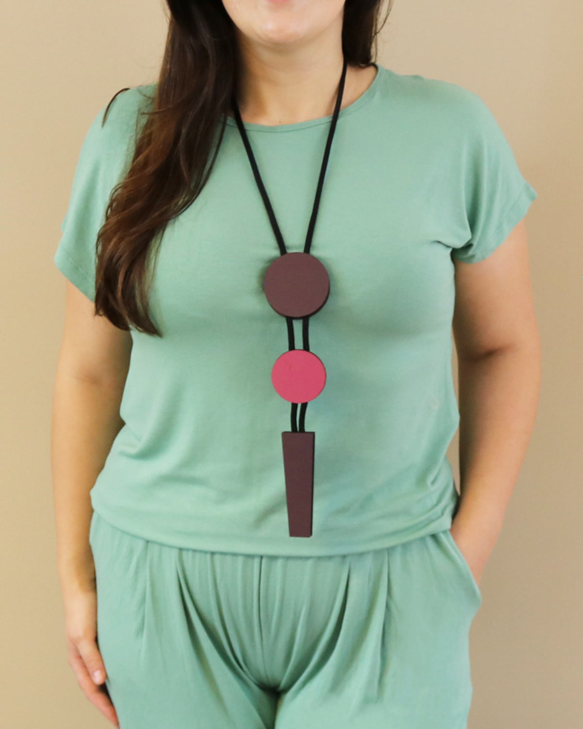 Colar Pêndulo Marrom e rosa usado sobre blusa lisa
