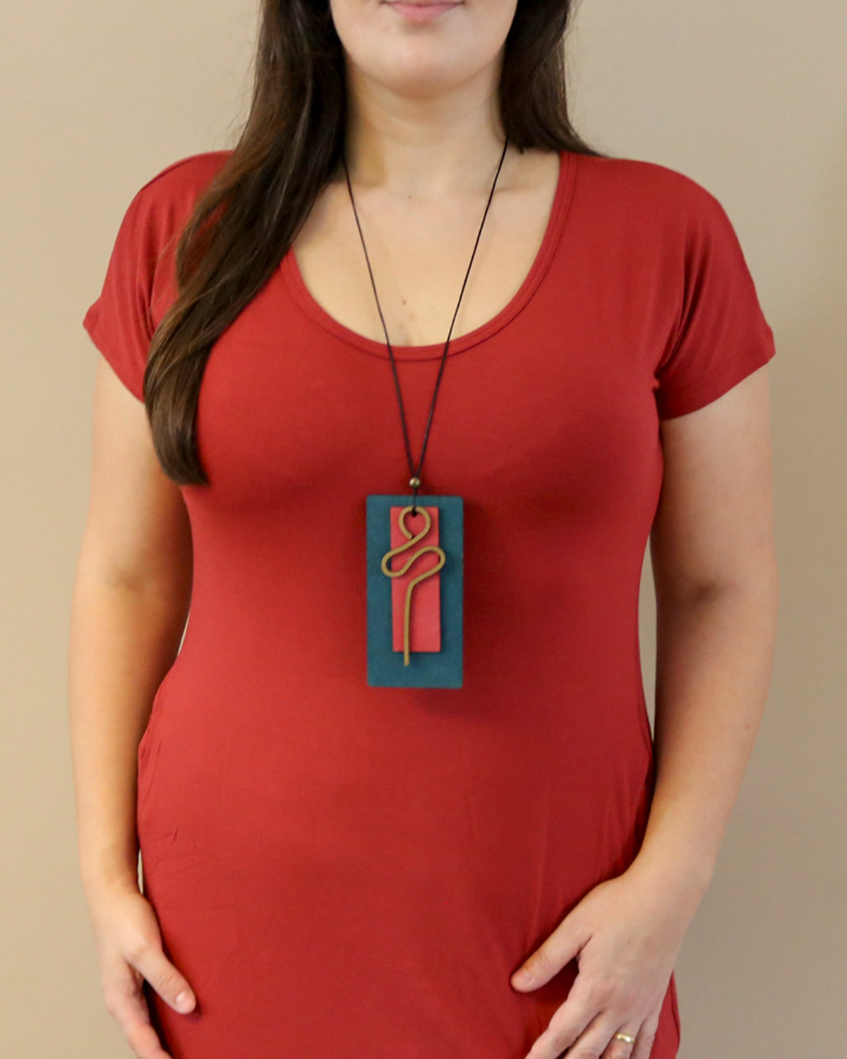Mulher com blusa vermelha usando o Colar Retângulo Azul/Rosa, de base azul e formas lineares coloridas